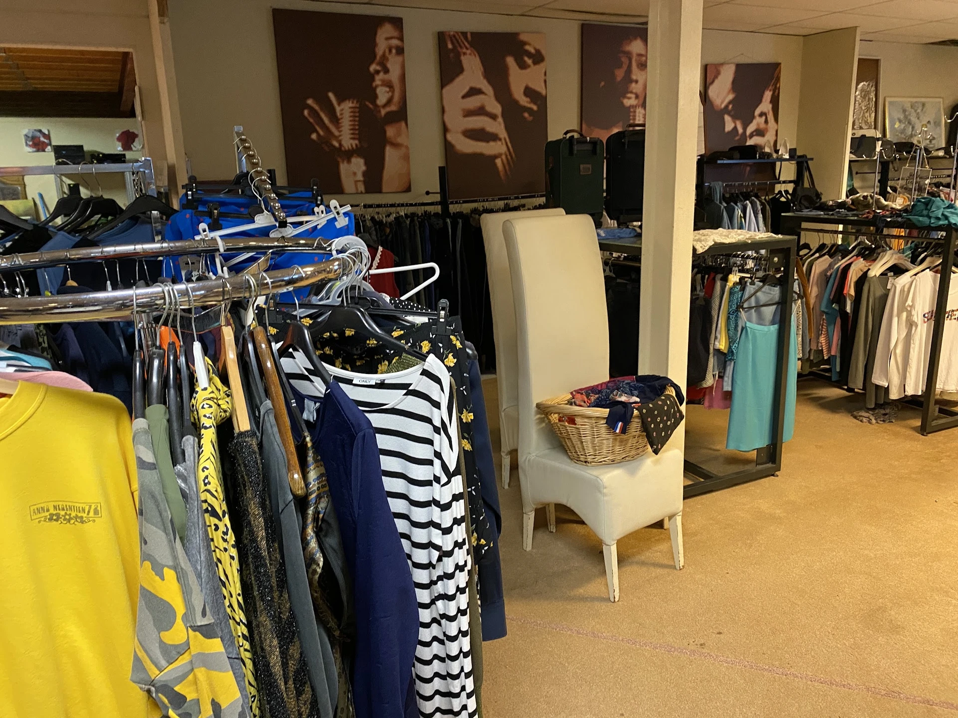 Winkelvloer met kledingrekken vol tweedehands kleding, toonbanken en winkelinrichting