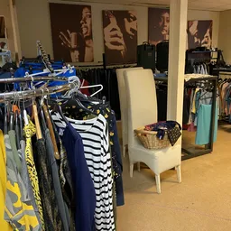 Winkelvloer met kledingrekken vol tweedehands kleding, toonbanken en winkelinrichting