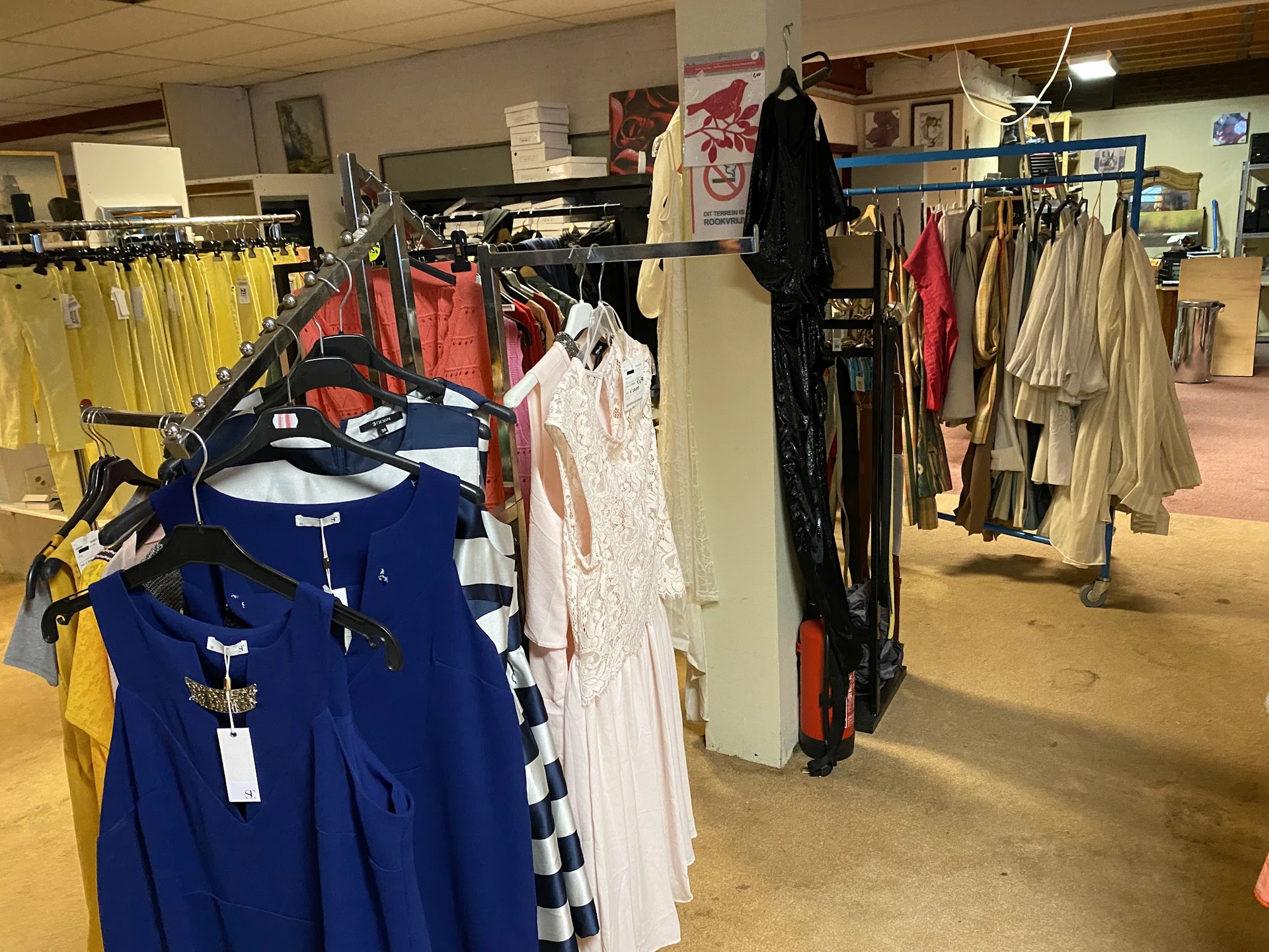 Rekken met tweedehands kleding in verschillende kleuren en stijlen in de winkel