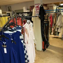 Rekken met tweedehands kleding in verschillende kleuren en stijlen in de winkel