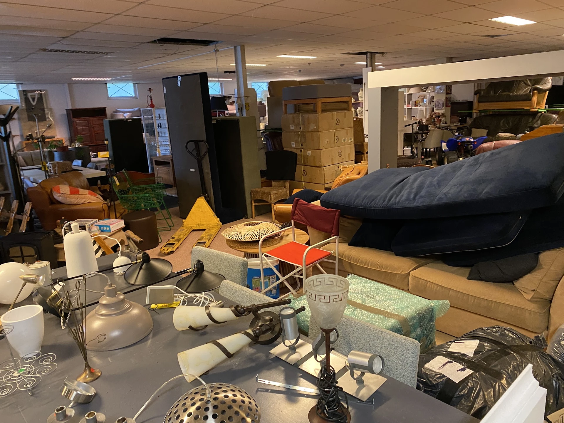 Rommelig winkelinterieur met dozen, meubels, huishoudartikelen en diverse spullen door elkaar