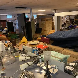 Rommelig winkelinterieur met dozen, meubels, huishoudartikelen en diverse spullen door elkaar