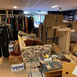 Winkelvloer met uitgepakte dozen, meubels, kledingrekken en diversen tweedehands spullen
