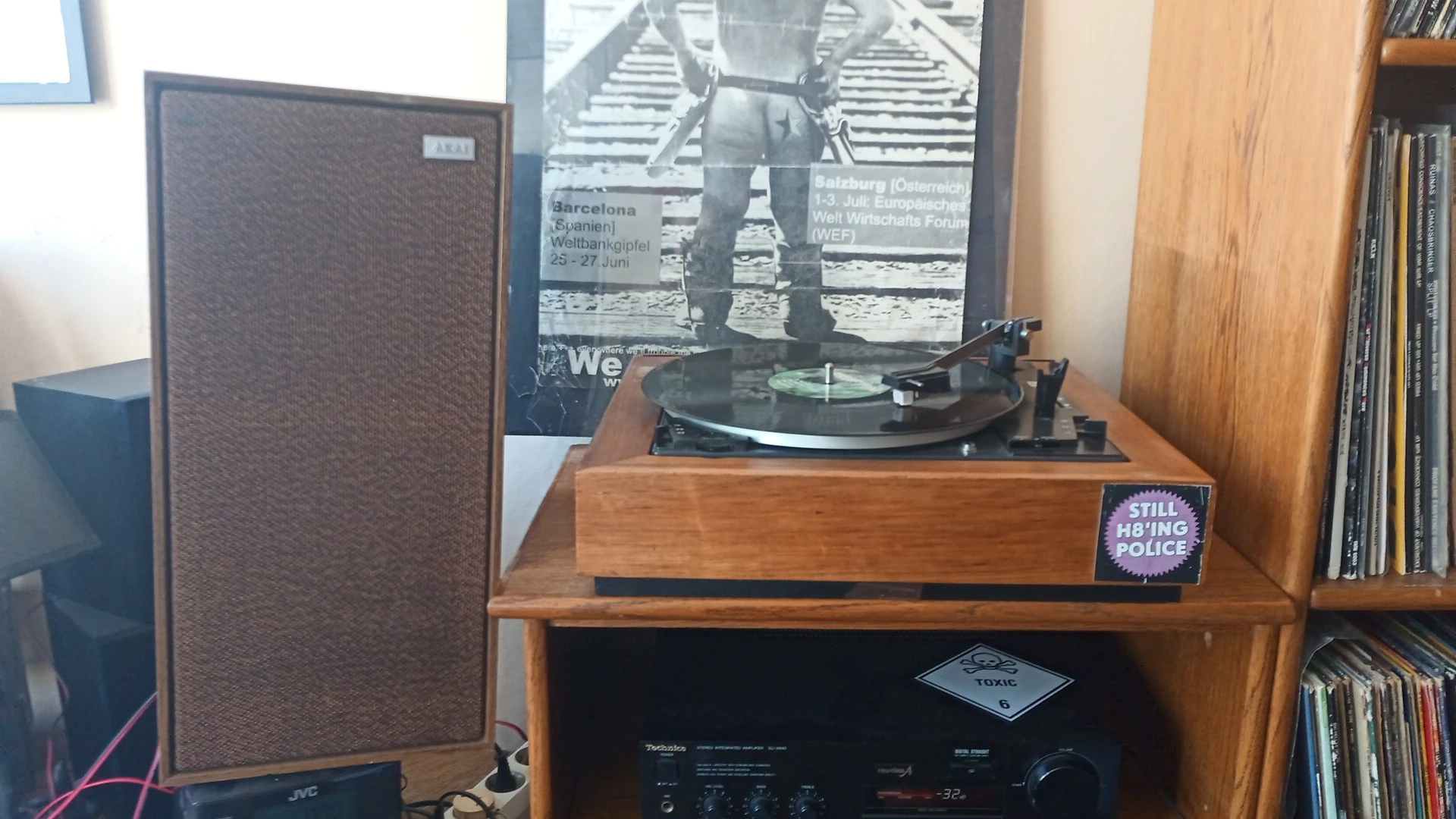 Vintage platenspeler in houten kast op een houten tafel, met versterker eronder en poster op de muur