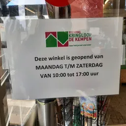 Openingstijdenbord met Kringloop de Kempen logo en openingsuren maandag tot zaterdag 10:00-17:00 uur