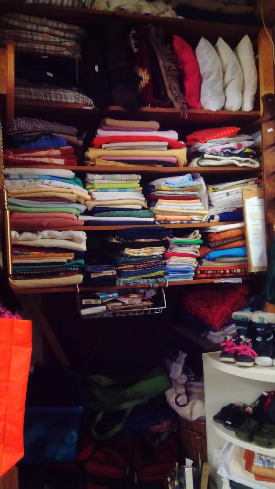 Kast met ingedeelde vakken vol met opgestapelde stoffen, textiel en quilts in verschillende kleuren