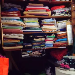 Kast met ingedeelde vakken vol met opgestapelde stoffen, textiel en quilts in verschillende kleuren