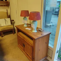 Houten dressoir met twee blauwe tafellampen met rode kappen in een kringloopwinkel