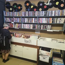 Winkelinterieur met cd- en dvd-afdeling, schappen vol media, en vinyl records aan de wand
