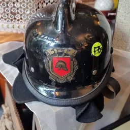 Zwarte glanzende brandweerman-helm met rood embleem en geel prijssticker van €3,50