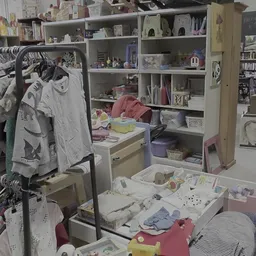 Binnenaanzicht van kringloopwinkel met open kasten, kleding op hangers en diverse spullen op tafels