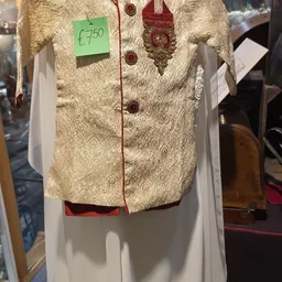 Crèmekleurig damestasje met ornamentale borduurwerk en rode knopen, op witte hanger tegen grijze wand.