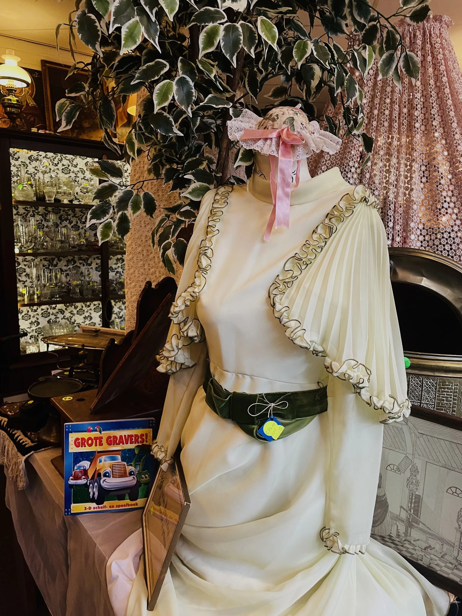 Crèmekleurige vintage jurk op etalagepop met geplooid mouwtje en groene ceintuur