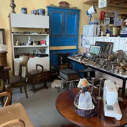 Winkelbinnenruimte met meubels, blauw kastje, stellingen en diverse huishoudelijke artikelen