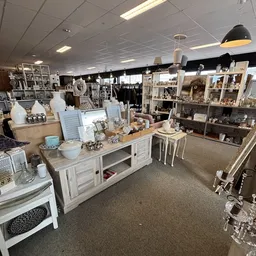 Overzicht van de winkelruimte met verschillende vitrines, een houten toonbank en diverse huishoudartikelen en decoratie.