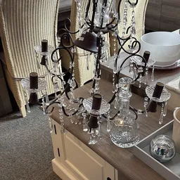 Kristallen kroonluchter met zwarte details en hangend kristal-ornamenten op houten tafel