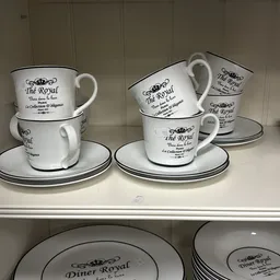 Serviesgoed 'The Royal' met zwarte decoratie: gestapelde kopjes en schotels op een plank