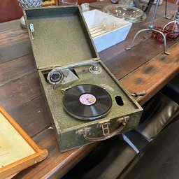 Vintage draagbare platenspeler in groen geval met zwart vinyl record op de draaitafel