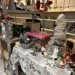 Uitgestalde decoratieartikelen en seizoensversieringen in een kringloopwinkel, waaronder kerstversiering, beelden en huisraad