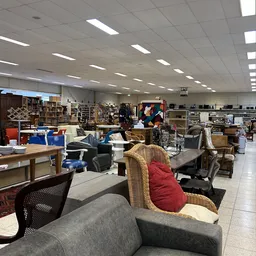 Winkelvloer van kringloopwinkel met diverse meubels, rekken en spullen uitgestald