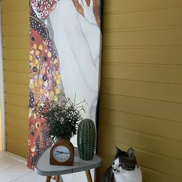 Hoek van winkelinterieur met gele wand, kunstwerk, klok, cactus en kat