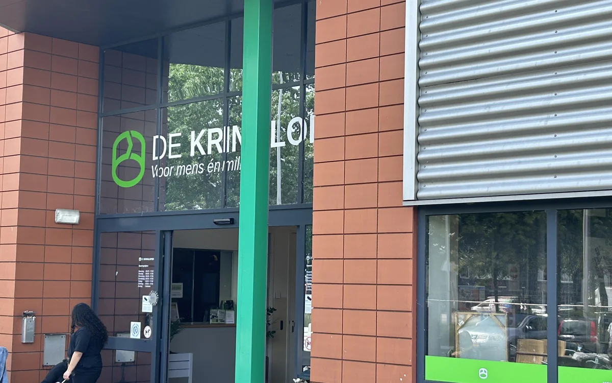 Ingang van kringloopwinkel met groene pijler, rode bakstenen gevel en groene accenten