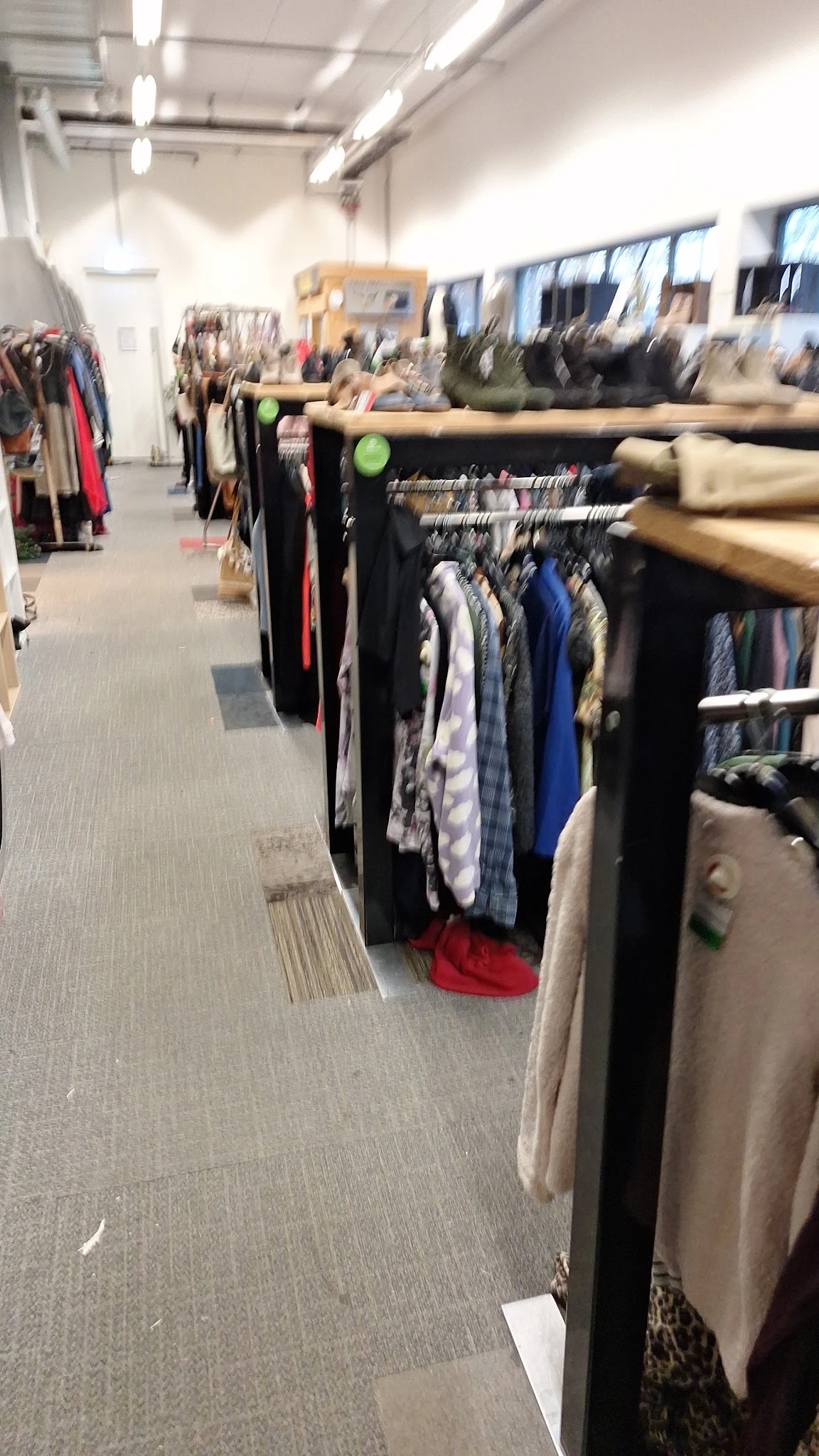 Rekken met tweedehands kleding in diverse kleuren en stijlen in de winkel