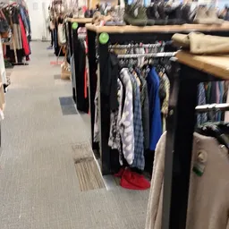 Rekken met tweedehands kleding in diverse kleuren en stijlen in de winkel