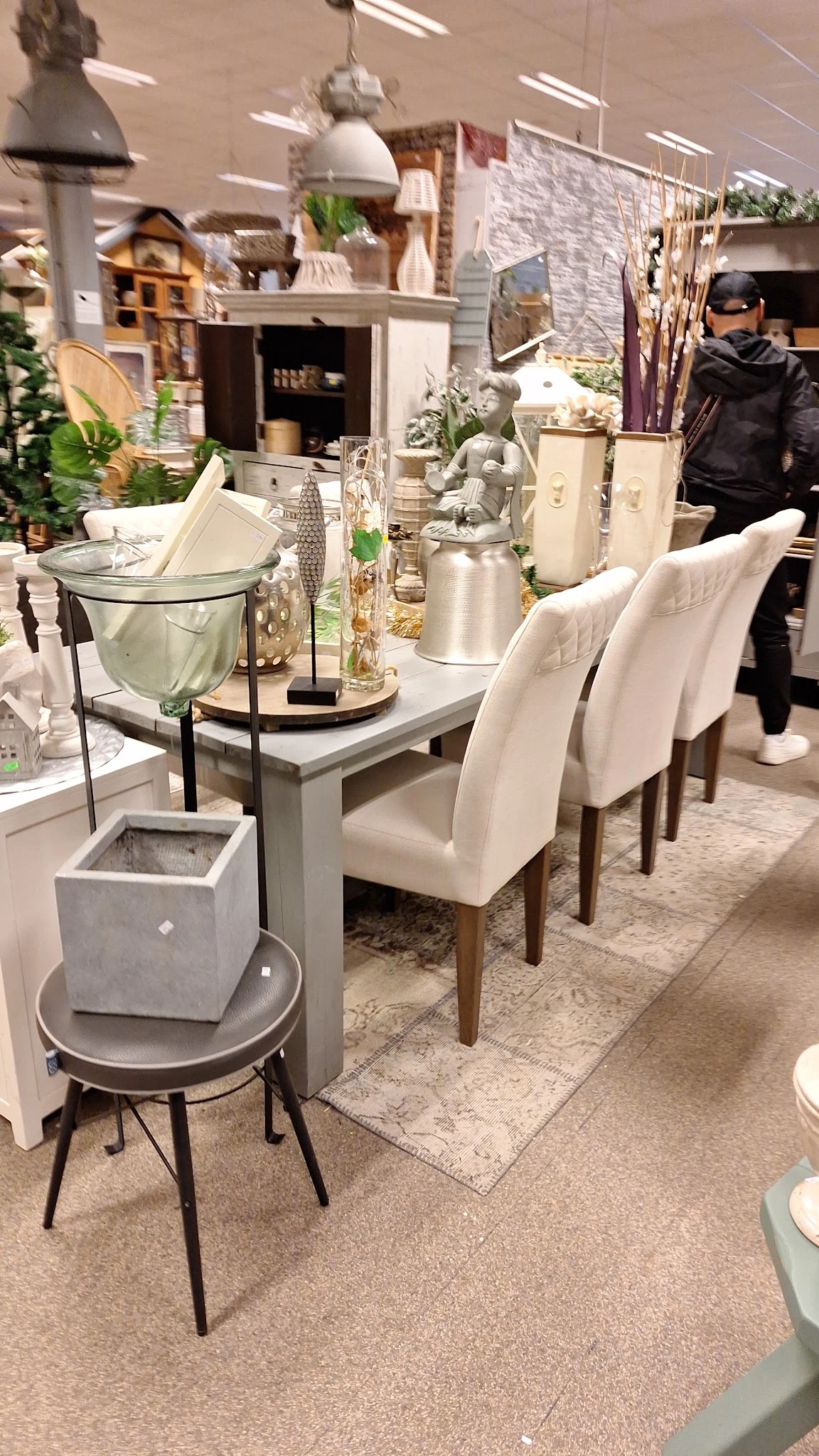 Grijze eettafel met witte stoelen en decoratieve accessoires in een interieurshow