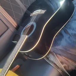 Zwarte akoestische gitaar met gouden inleggen, close-up van voorkant en zijkant