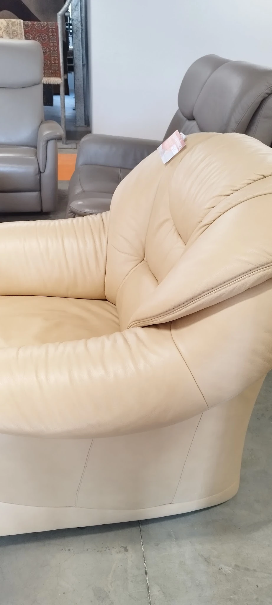 Close-up van een crèmekleurig lederen fauteuil met armleuningen en gestikte details