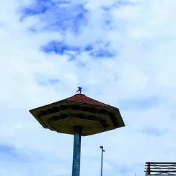 Uitstekende lamp met donkerrood dak tegen blauwe lucht