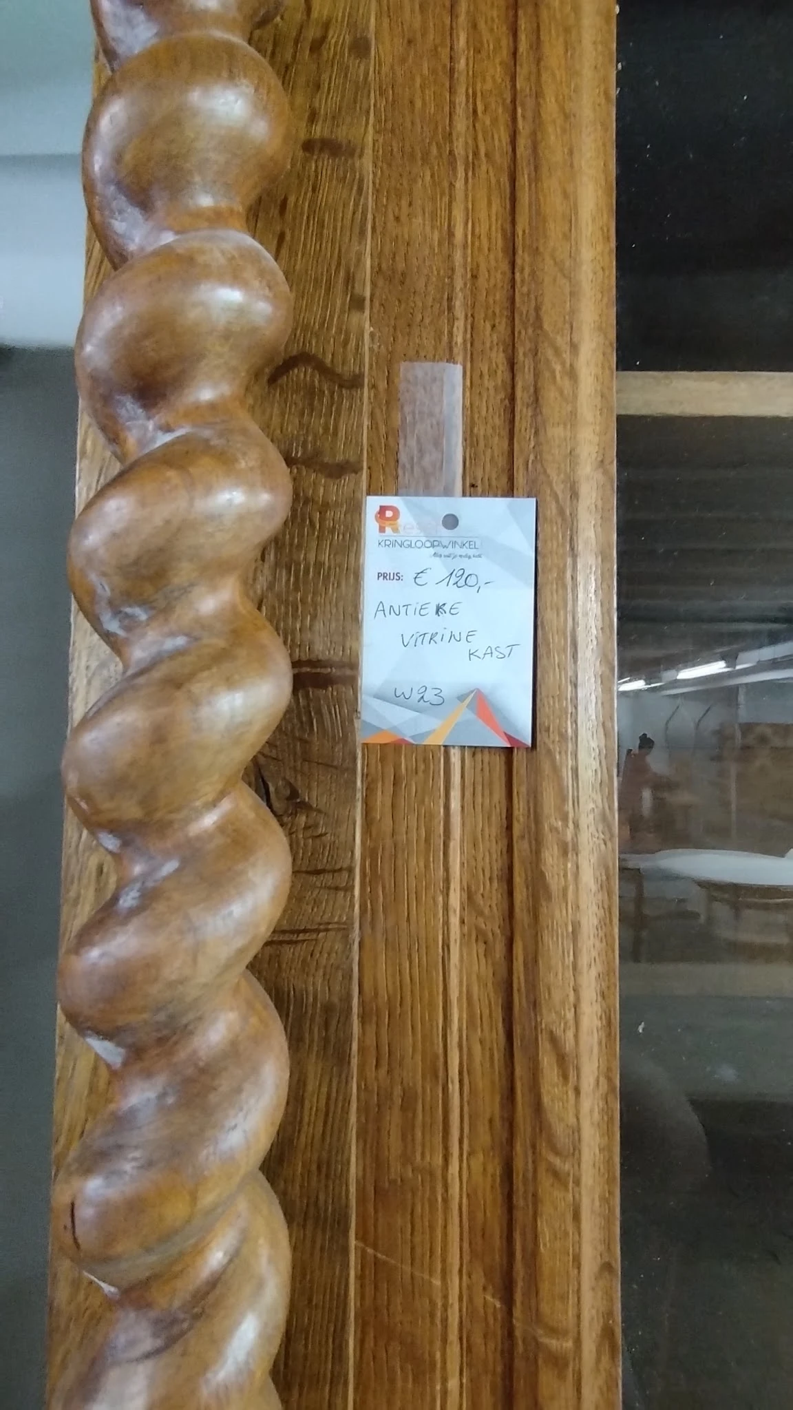 Houten beeldhouwwerk van drie verbonden bollen op houten wand met prijskaartje