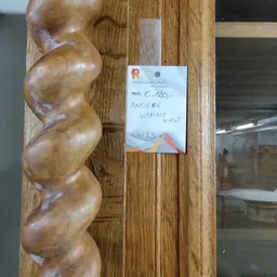 Houten beeldhouwwerk van drie verbonden bollen op houten wand met prijskaartje