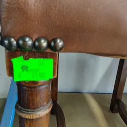 Houten object met vier metalen bollen bovenop, met een groen element in het midden