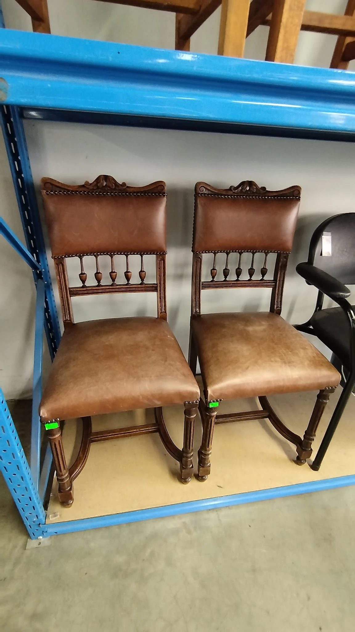 Twee bruinleren stoelen met houten frame en decoratieve nagelingen op de zitting