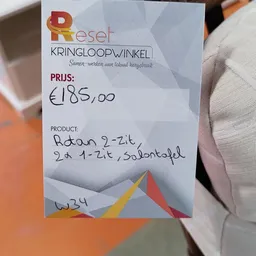 Handgeschreven prijskaartje van kringloopwinkel met prijs €185,00 en productbeschrijving
