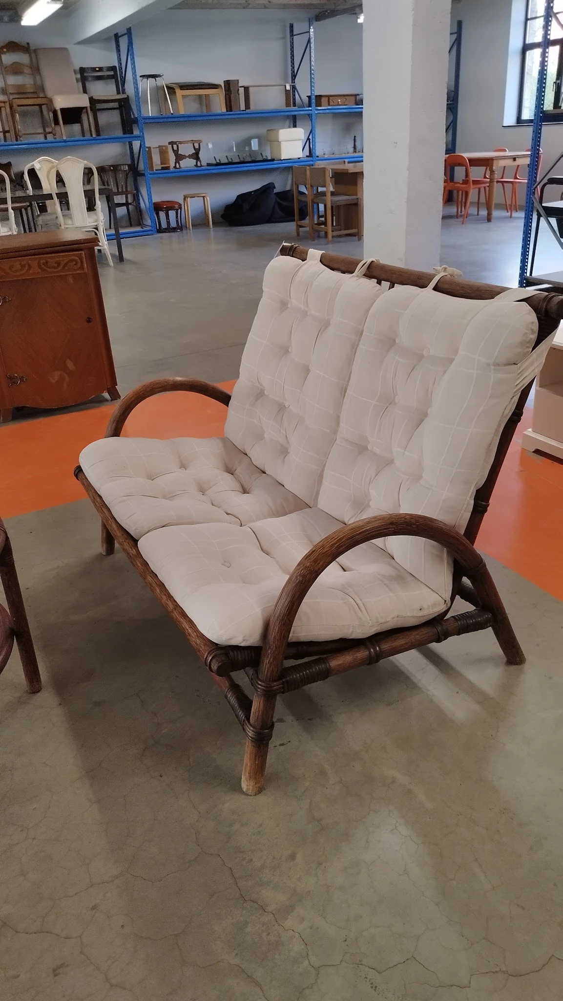 Houten fauteuil met witte gestoffeerde zitting en rugleuning op oranje vloer