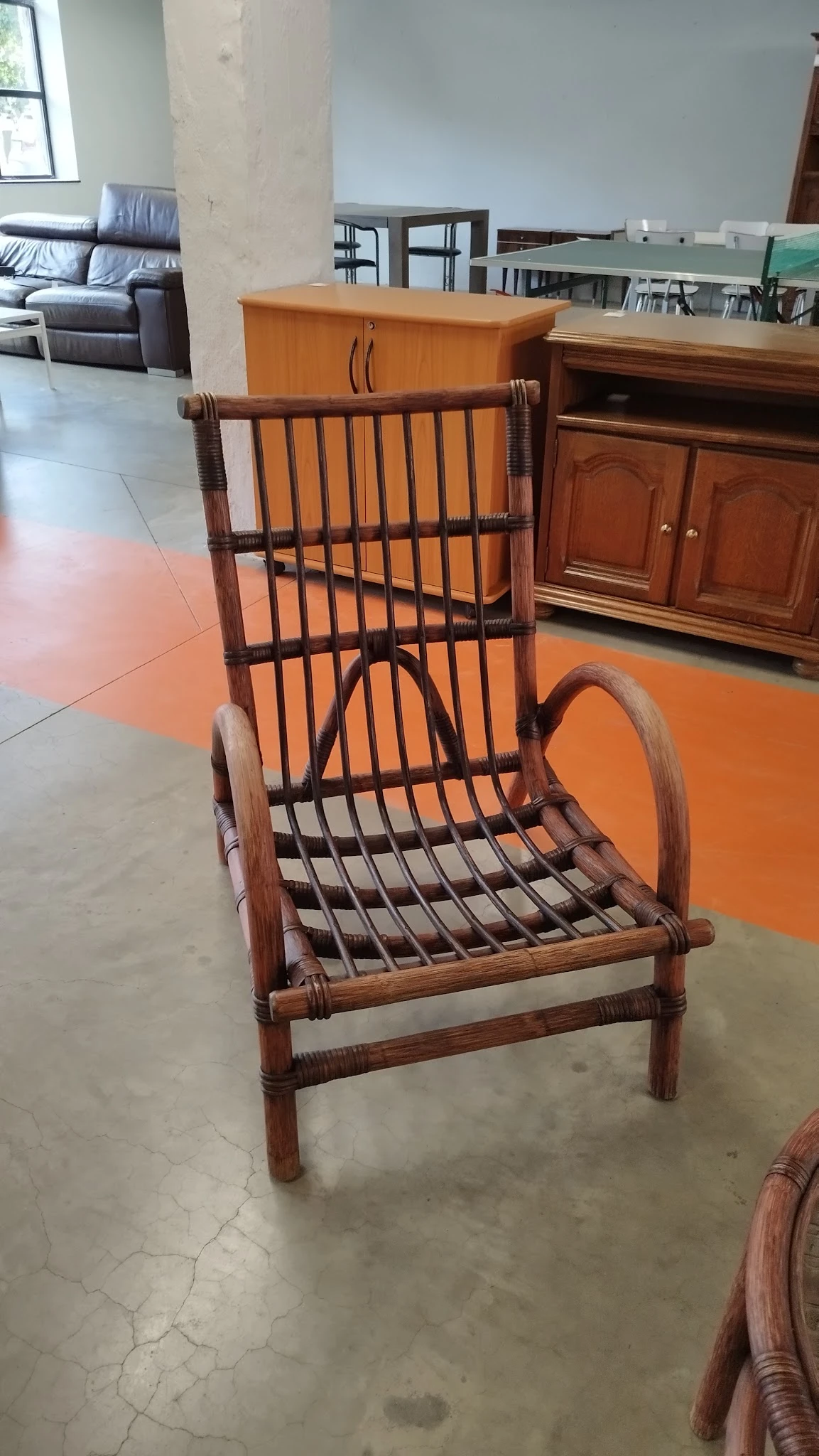 Houten fauteuil met rieten/rotan zitting en rugleuning, bruin gekleurd, staand in een kringloopwinkel
