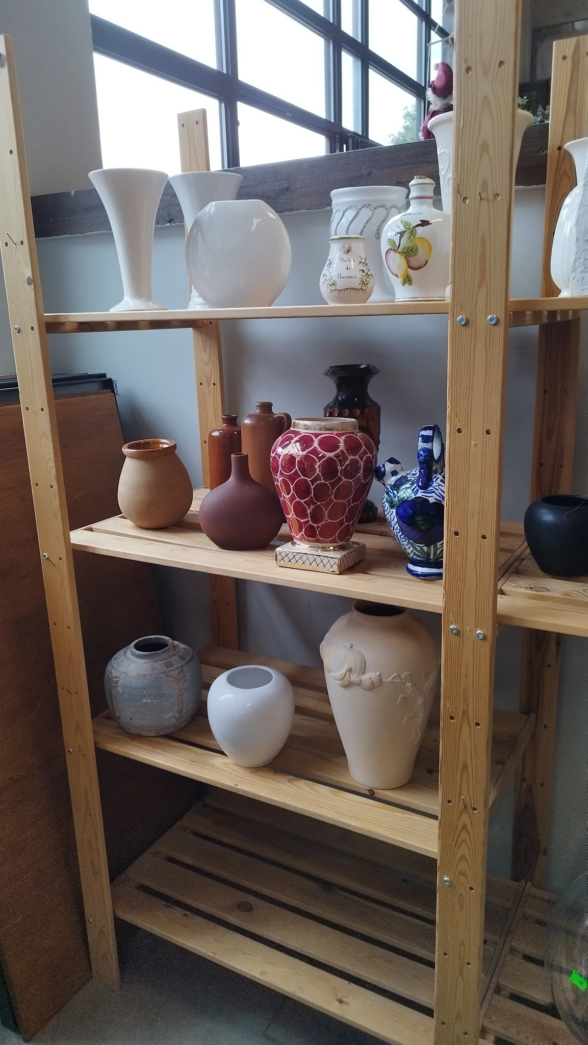 Houten stellingkast met decoratieve vazen en potten in verschillende kleuren en stijlen