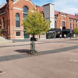 Marktplein met bakstenen gebouwen, jong boompje en zwart paviljoen