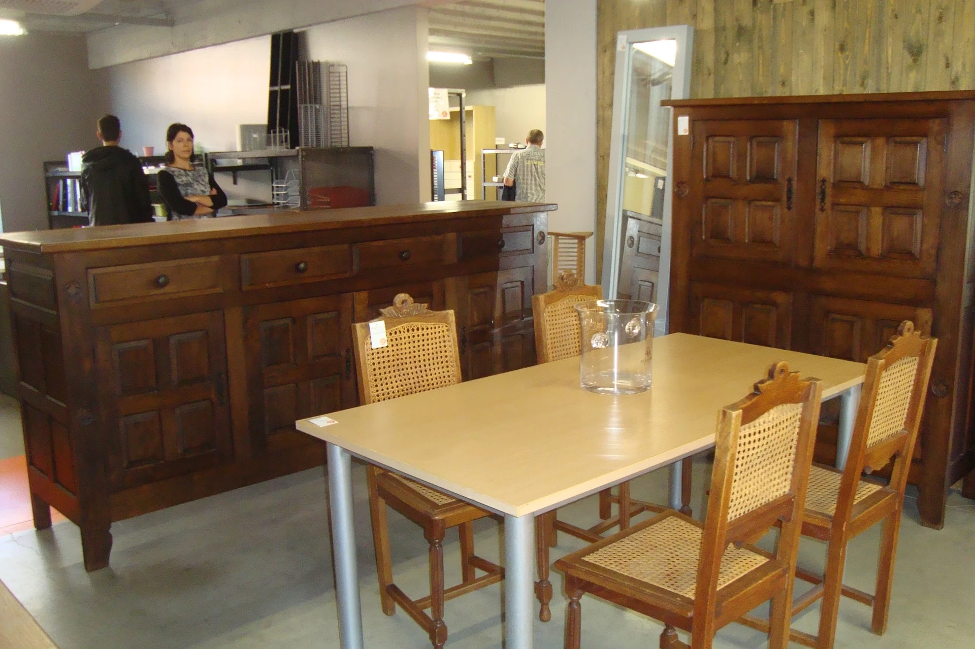 Winkelbinnenruimte met eettafel en stoelen, houten meubels op de achtergrond en balie met personeel