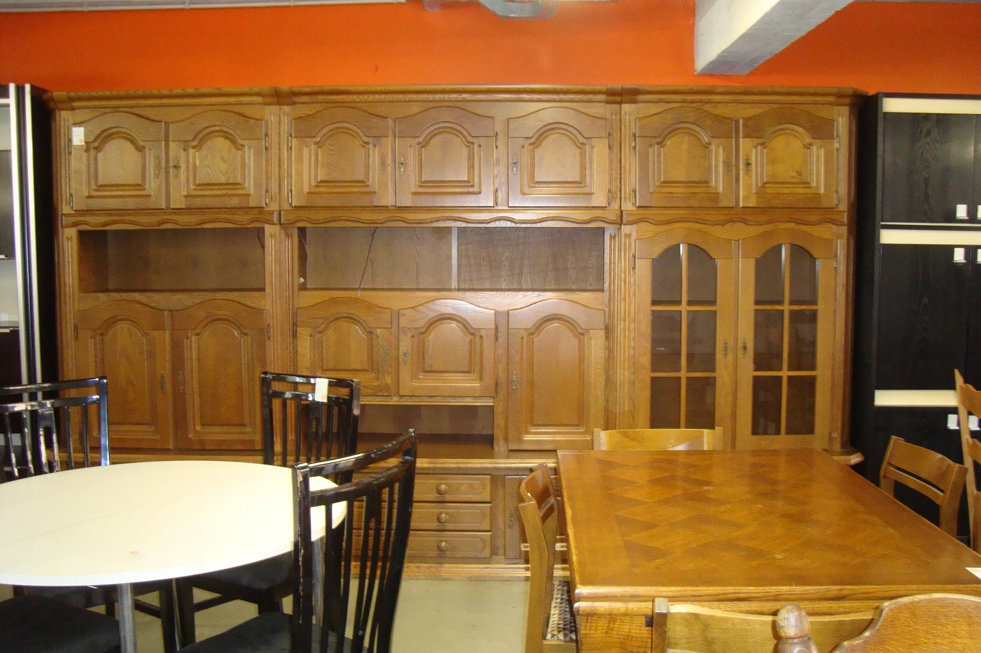 Houten kasten en meubelen in een kringloopwinkel, inclusief een eettafel en stoelen