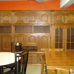Houten kasten en meubelen in een kringloopwinkel, inclusief een eettafel en stoelen