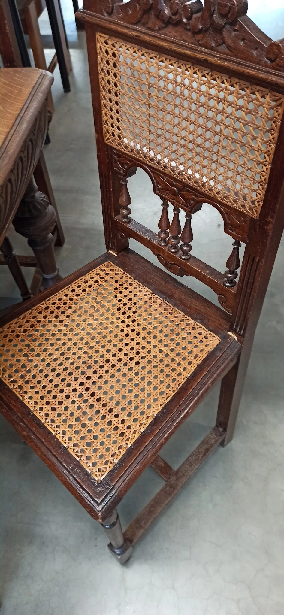 Close-up van een houten stoel met gevlochten rotan zitting en gesneden rugleuning