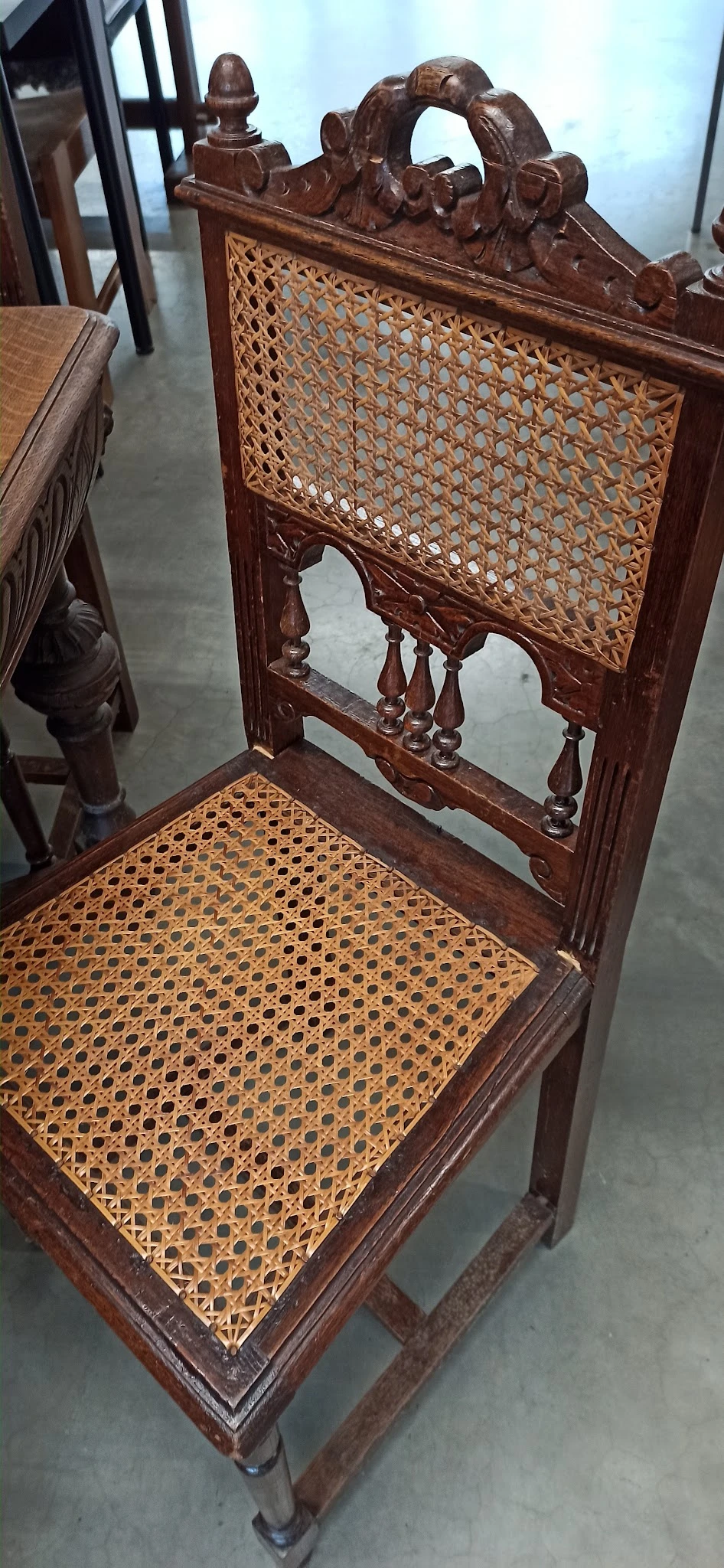 Gedetailleerde close-up van een antieke houten stoel met gevlochten zitting en decoratief gesneden rugleuning