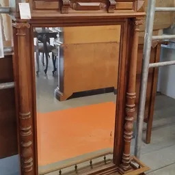 Houten spiegellijst met bruine bewerking en oranje reflectie in de spiegel