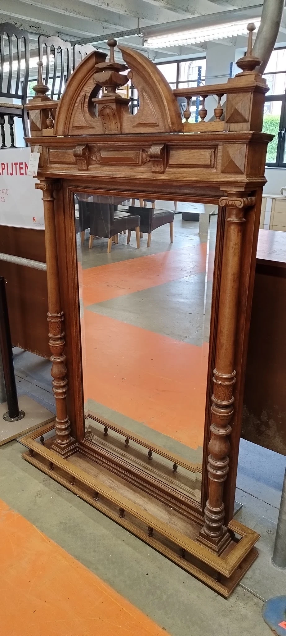 Winkelvloer met oranje en grijze tegels, houten deurposten, enkele meubels op achtergrond