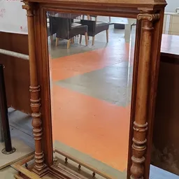Winkelvloer met oranje en grijze tegels, houten deurposten, enkele meubels op achtergrond