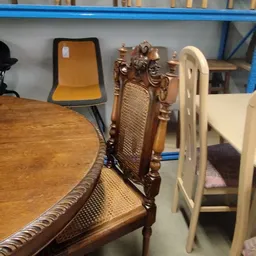 Verschillende meubels in de winkel: houten stoelen met decoratief snijwerk, een gele stoel en witte stoelen